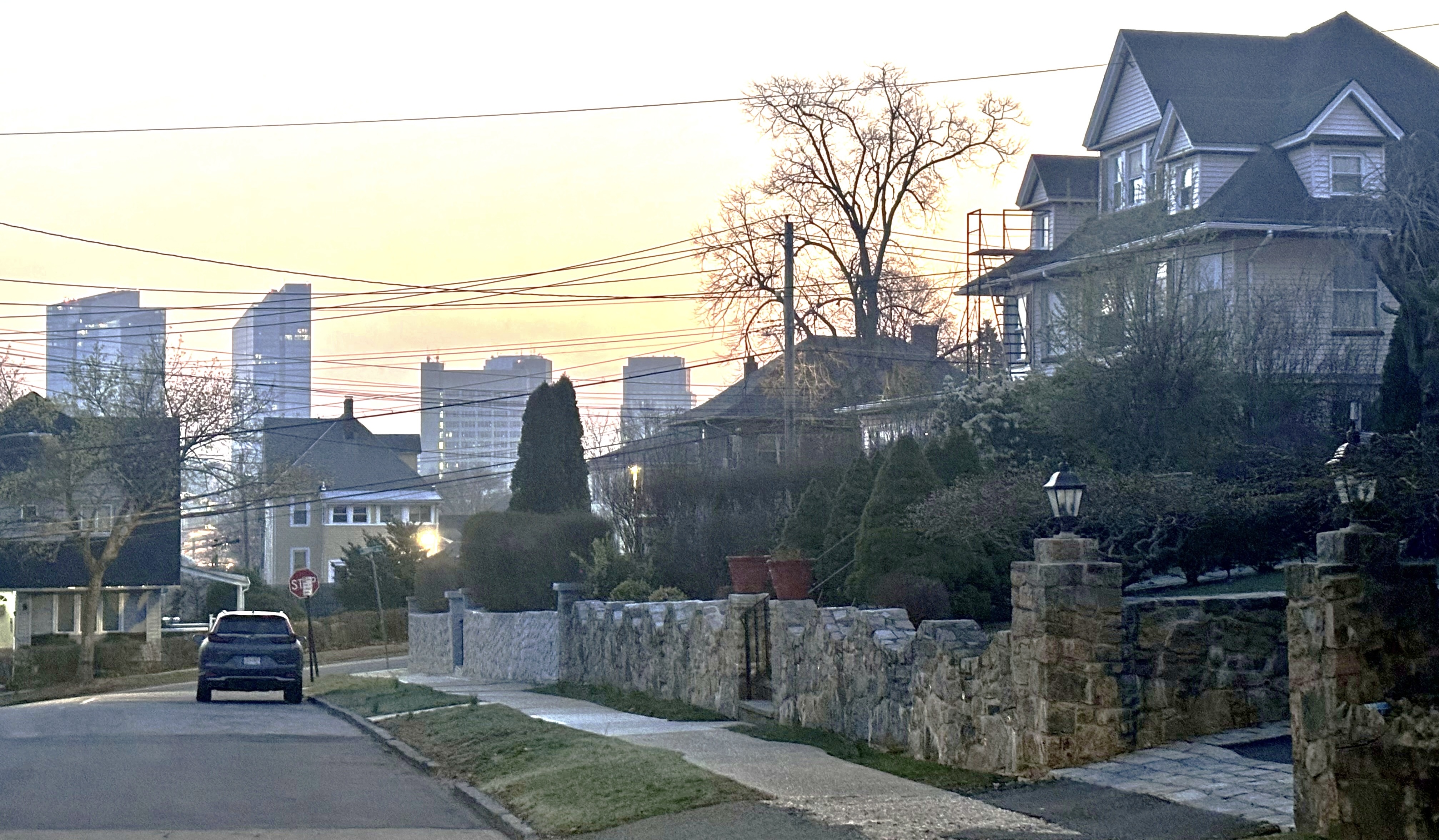 Fisher Hill residential street with stone walls, historic homes, and downtown White Plains towers in the distance.